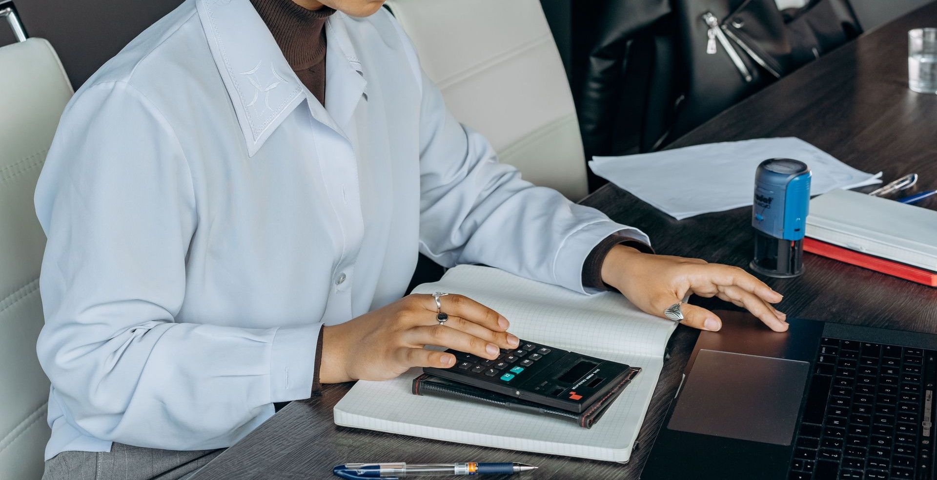 Young woman in office using a calculator for financial calculations.